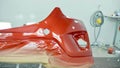 Car bumper after painting in a cars spray booth. Vehicle cherry color bumper Royalty Free Stock Photo