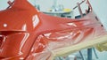 Car bumper after painting in a cars spray booth. Vehicle cherry color bumper