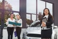Car buy procedure. Woman dealer with tablet and buyers with folder standing near car