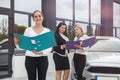 Car buy procedure. Woman dealer with tablet and buyers with folder standing near car