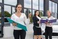 Car buy procedure. Woman dealer with tablet and buyers with folder standing near car