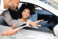 Car Buyers Choosing New Family Autombile With Seller In Store