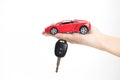 Car buying concept. A hand holding a car key with a toy car on a white background Royalty Free Stock Photo