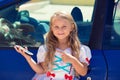 Car calling taxi app searching concept. Little girl kid child showing at the phone screen standing near a blue car Royalty Free Stock Photo