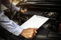 Close-up hand technician auto mechanic using checklist after repair change spare part car