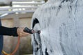 Car care shop. Worker holding spray head and inject to cleaning car by chemical foam for washing car