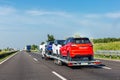 Car carrier trailer with new blue white and red car on highway