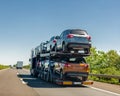 Car carrier trailer with cars on bunk platform. Car transport truck on the highway