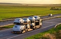 Car carrier trailer transports cars on highway on sunset background. Auto transport and car shipping services concept. Truck with Royalty Free Stock Photo
