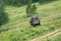 A car with children on the roof stands on a steep slope of forest glade in the summer