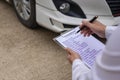 Car claim process Insurance agent after car accident writes on clipboard while inspecting Royalty Free Stock Photo