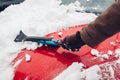 Car cleaning from snow using broom. Man taking care of automobile bumper removing ice with brush outdoors