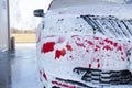 Car cleaning. Wash red car with soap. High pressure water washing close-up