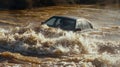 A car is completely submerged in murky brown water its headlights ly visible as the rapid current carries it away