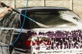 The car is covered with foam at a self-service car wash, Close up man hand is washing a  car using high pressure water jet and Royalty Free Stock Photo