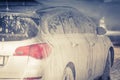 The car is covered with foam at a self-service car wash. Man washes foam machine. Carwash. Washing machine at the station Royalty Free Stock Photo