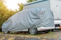 The car is covered with a protective cover from the effects of rain and snow in the parking lot, storage secured parking Royalty Free Stock Photo