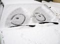 Car covered with snow with a painted on the windshield mug