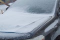 The car is covered with snow on a winter day, front window windshield and hood view on a snowy background Royalty Free Stock Photo