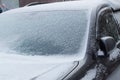 The car is covered with snow on a winter day, front window windshield and hood view on a snowy background Royalty Free Stock Photo