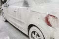 car is covered with white foam in the car wash in the garage. Self-washing machine. Automatic car wash Royalty Free Stock Photo