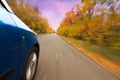 A car on curvy autumn forest road, with motion blur from its speed