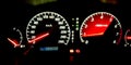 Car dashboard illuminated at night with red