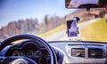 Car dashboard with smartphone used as navigation device, bright and sunny day