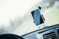 Car dashboard with smartphone used as navigation device, bright and sunny day