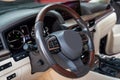 Car dashboard and steering wheel with media control buttons. Beige cockpit with exclusive wood decoration. Luxury