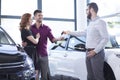Car dealer giving car keys to a happy married couple Royalty Free Stock Photo