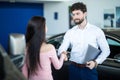 Car dealer handshaking with happy female in automobile center