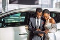 Car dealer showing vehicle to black woman Royalty Free Stock Photo