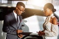 Car dealer showing vehicle to black woman Royalty Free Stock Photo