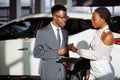 Car dealer showing vehicle to black woman Royalty Free Stock Photo