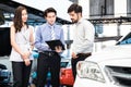 Car Dealership. The Asian Salesman woman and man checking the list with the middle east customer before hand over.