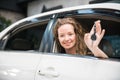 Car dealership. The woman showing a car key in her palm with smiling while sitting inside the car Royalty Free Stock Photo