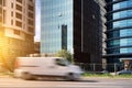 A car with a delivery service van drives quickly along the road in the city against the backdrop of skyscrapers