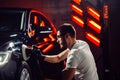 Car detailing - man with orbital polisher in auto repair shop. Selective focus.