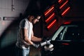 Car detailing - man with orbital polisher in auto repair shop. Selective focus.