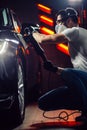 Car detailing - man with orbital polisher in auto repair shop. Selective focus. Royalty Free Stock Photo