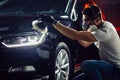 Car detailing - man with orbital polisher in auto repair shop. Selective focus.