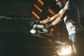 Car detailing - man with orbital polisher in auto repair shop. Selective focus. Royalty Free Stock Photo