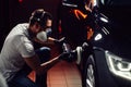 Car detailing - man with orbital polisher in auto repair shop. Selective focus. Royalty Free Stock Photo