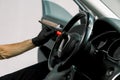 Car detailing and interior care concept. Hand of male worker in protective rubber gloves, cleaning the steering wheel of