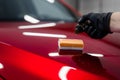 Car detailing - Man applies nano protective coating or wax on red car. Covering car bonnet with a liquid glass polish.