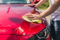 Car detailing - the man holds the microfiber in hand and polishes the car. Man worker washing car`s alloy wheels on a car wash. Royalty Free Stock Photo