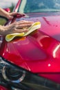 Car detailing - the man holds the microfiber in hand and polishes the car. Man worker washing car`s alloy wheels on a car wash. Royalty Free Stock Photo