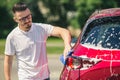 Car detailing - the man holds the microfiber in hand and polishes the car. Man worker washing car`s alloy wheels on a car wash. Royalty Free Stock Photo