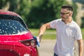 Car detailing - the man holds the microfiber in hand and polishes the car. Man worker washing car`s alloy wheels on a car wash. Royalty Free Stock Photo